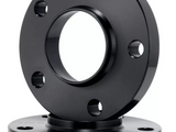 A black circular metal flange with a central hole and multiple bolt holes is displayed in front of a similar flange, set against a plain white background.