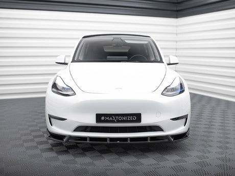 A white car is parked in a futuristic showroom with striped walls and a checkered floor. The license plate displays "#MAXTONIZED."