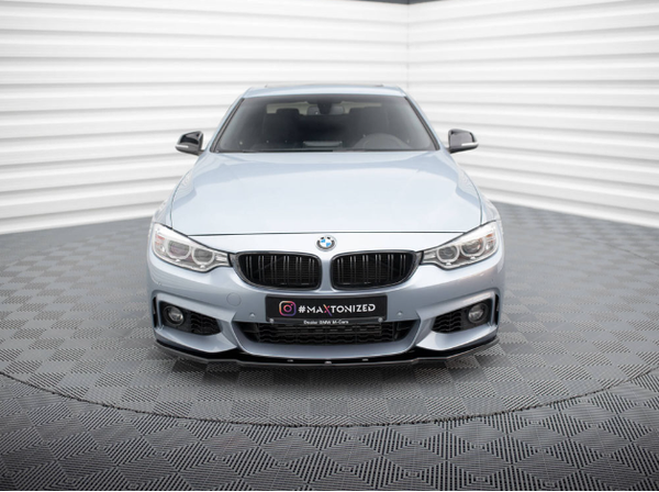 A light blue BMW car is parked in a corner of a showroom with textured walls and floor, featuring the license plate text: "@MAXTONIZED www.MAXTONDESIGN.eu."