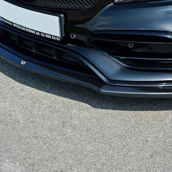 The front bumper of a sleek, black car with intricate vents and a glossy finish sits on a sunlit asphalt road. Text: "Mercedes-Benz INTER-CAR RYBNIK tel. 32 888 53 01".