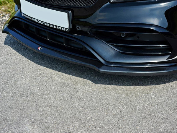 The front bumper of a sleek, black car with intricate vents and a glossy finish sits on a sunlit asphalt road. Text: "Mercedes-Benz INTER-CAR RYBNIK tel. 32 888 53 01".