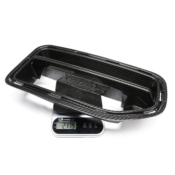 A carbon fiber car part rests on a digital scale reading "217.5" grams, set against a plain white background.