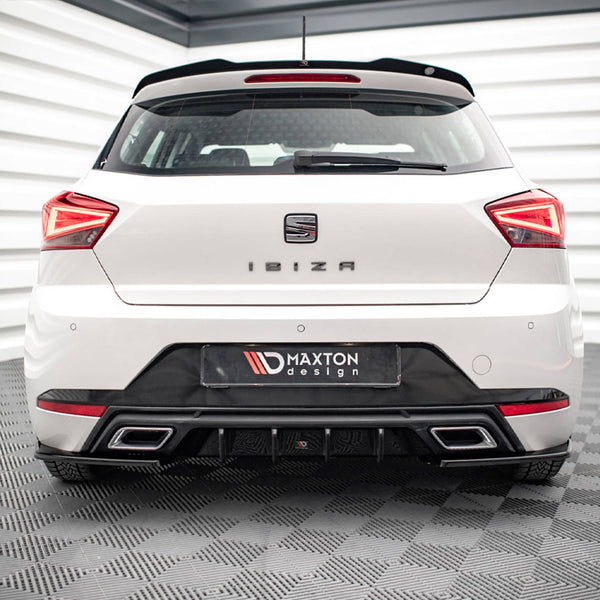 A white car is parked in a showroom. The rear features the text "IBIZA" and "MAXTON design," with distinct taillights and a sleek bumper. The room has checkered flooring.