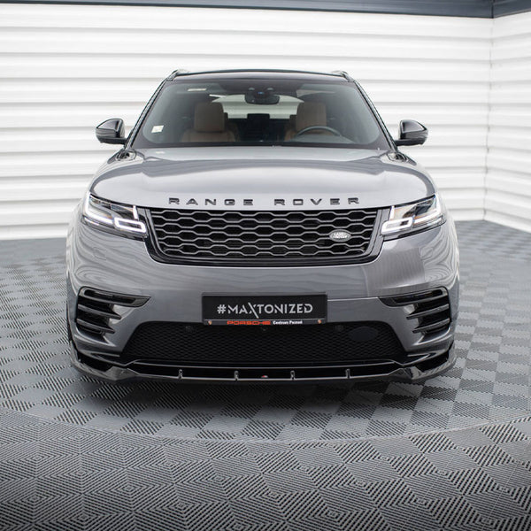 A Range Rover is parked in a modern showroom with a checkered floor and white walls. The grille and headlights are prominent. Text on the front reads: “#MAXTONIZED.”