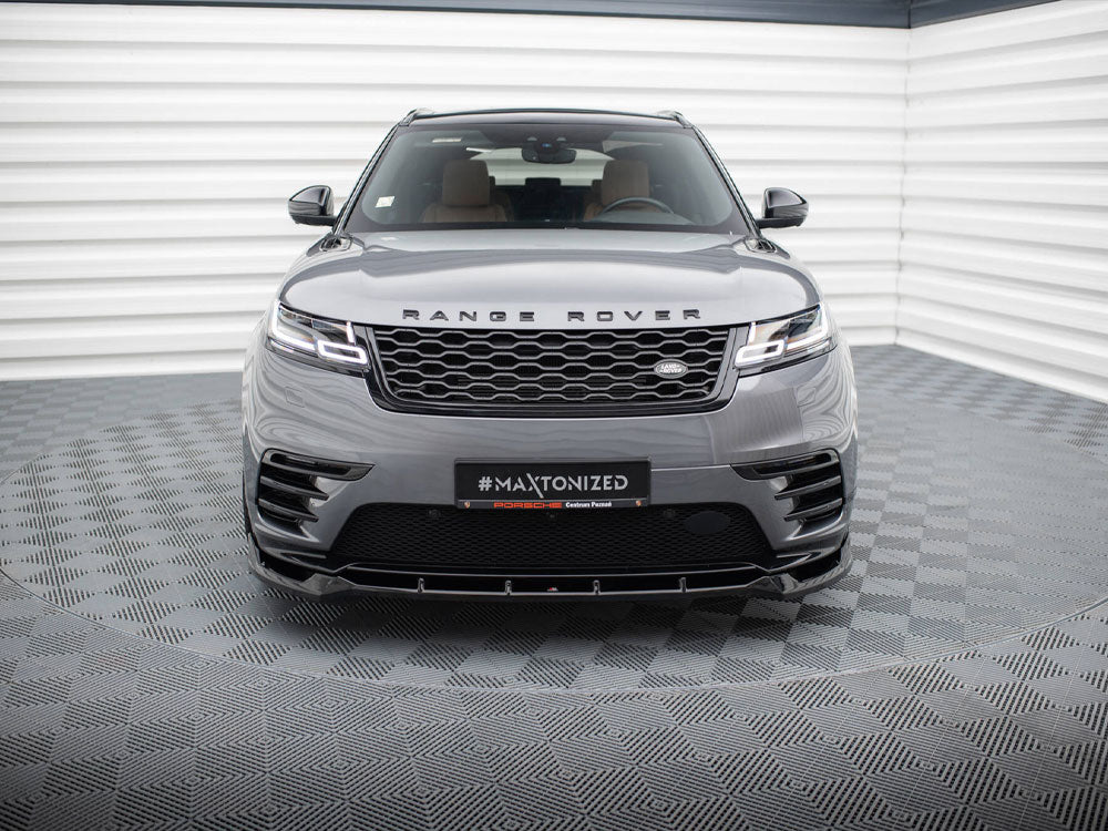 A Range Rover is parked in a modern showroom with a checkered floor and white walls. The grille and headlights are prominent. Text on the front reads: “#MAXTONIZED.”