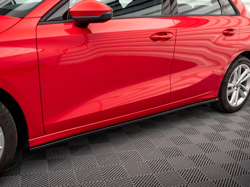 Red car parked on a patterned floor with reflections visible on the shiny surface, showing a side view including doors, wheels, and a side mirror.