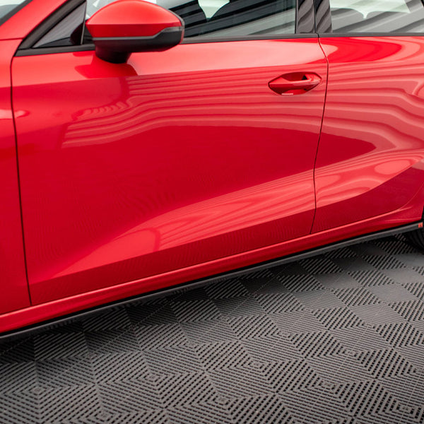 Red car parked on a patterned floor with reflections visible on the shiny surface, showing a side view including doors, wheels, and a side mirror.