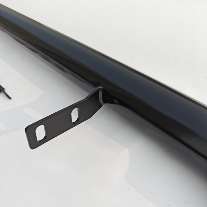 A black metal rod with two bracket holes protrudes from its side, resting on a white surface with shadowy reflections.
