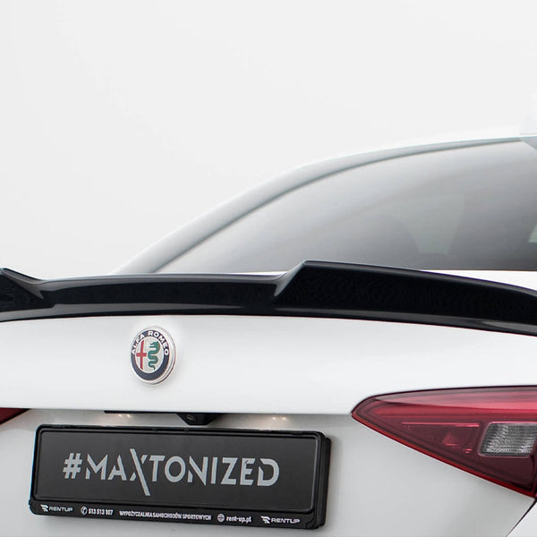 A white car has a black spoiler attached to its trunk. The logo "ALFA ROMEO" is visible, along with "#MAXTONIZED" text on the license plate. The background is plain white.