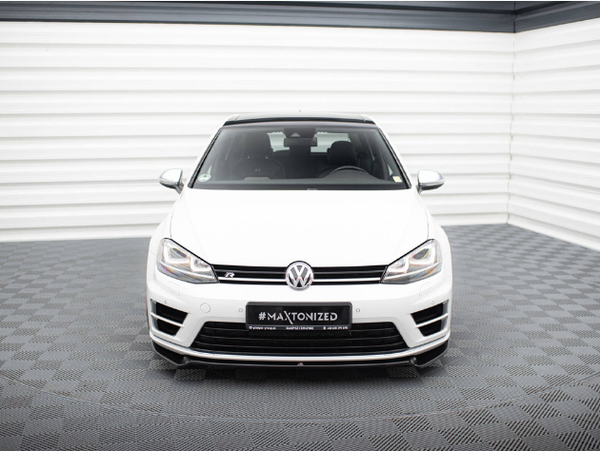A white Volkswagen car is parked in a showroom with a checkered floor and striped walls. The license plate reads "#MAXTONIZED."