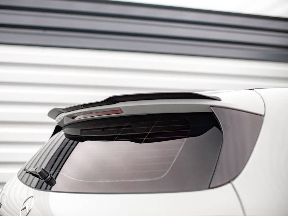 Car rear window with a partially visible wiper and a spoiler above. The vehicle is parked in front of a white, horizontal-striped wall, providing a modern backdrop.