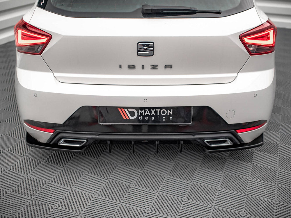 A white car's rear, labeled "IBIZA," is stationary on a patterned floor. The license plate reads "MAXTON design," surrounded by distinctive taillights and a dual exhaust.