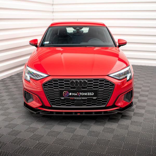Red car displayed stationary in a white-paneled showroom with a textured grey floor. The license plate reads "#MAXTONIZED Audi Centrum Kielce."