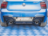 A blue BMW M135i is parked on a blue patterned floor with visible dual exhausts. The license plate reads 