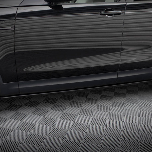 A black SUV side view shows reflections on its surface with "DISCOVERY" text near the front door. It stands parked on a textured gray floor, showcasing two tires.