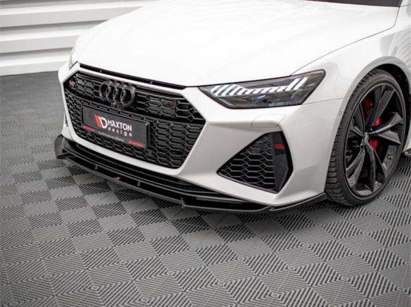 A white car with sleek headlights and a black grille, featuring the text "Maxton Design." It is parked indoors on a patterned floor, showcasing modern design and detailing.