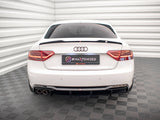A white Audi car is stationary in a room with white, ribbed walls and checkered flooring. The rear license plate displays 