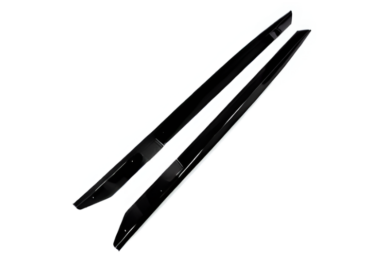 Two sleek, black, elongated plastic car side skirt extensions lie parallel on a white surface, appearing glossy and streamlined, designed for vehicle body modification.
