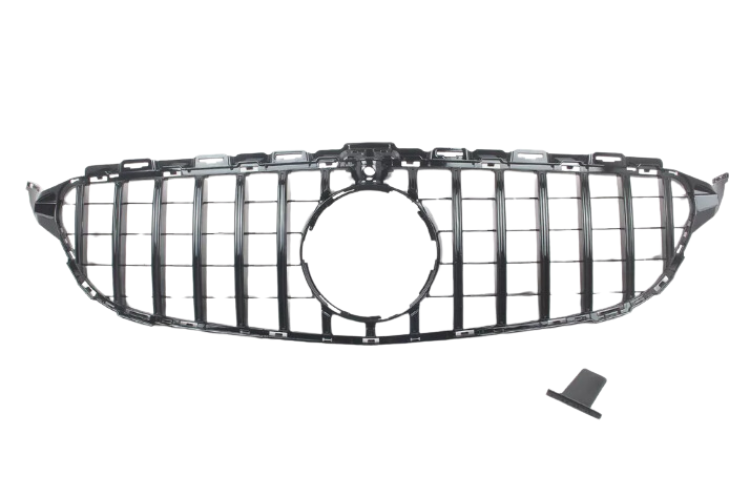 A car grille with vertical slats, designed for a front bumper, includes a circular central opening, placed on a plain white background. A small, detached piece lies nearby.