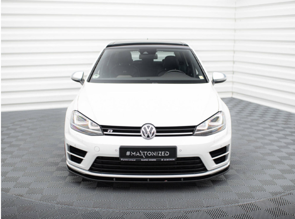 A white Volkswagen car is parked in a well-lit showroom with geometric patterned flooring and white walls. The license plate reads "#MAXTONIZED" with additional details below.