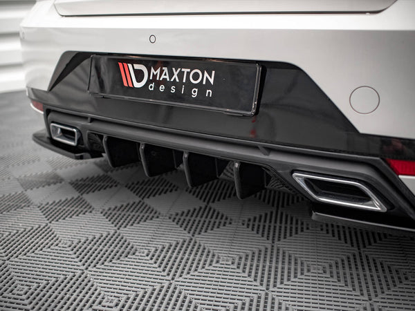 Car's rear bumper features dual exhaust outlets and diffuser; black "MAXTON design" license plate is displayed; parked on textured gray flooring in an indoor setting.