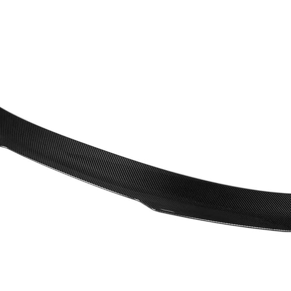 A carbon fiber car spoiler with a sleek, curved design rests against a plain white background, highlighting its aerodynamic structure and lightweight material.