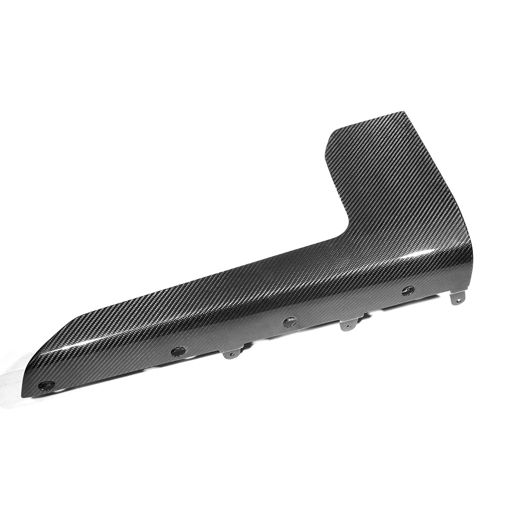 A sleek, carbon-fiber auto component rests on a plain white surface, showcasing a glossy, textured finish with visible attachment points along its edge.