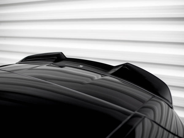 A shiny black car roof features an aerodynamic fin. It's positioned against a blurred, horizontally-striped, white background, creating a sleek and modern appearance.