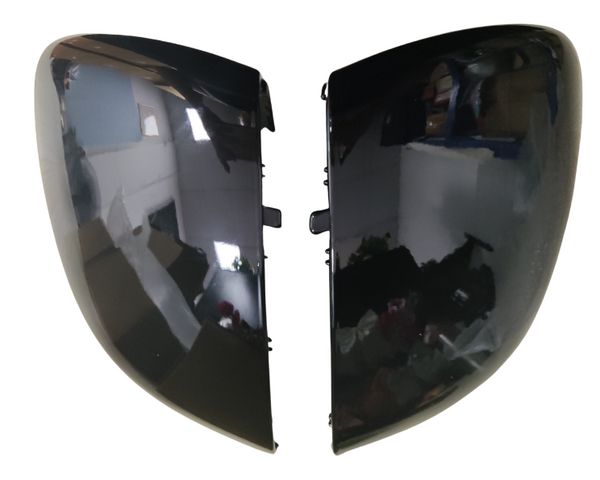 Two black mirror covers lie side by side with reflective surfaces, capturing room reflections in a brightly lit, indoor environment.