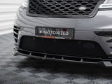 A car's front bumper with a grille displays a plaque reading 