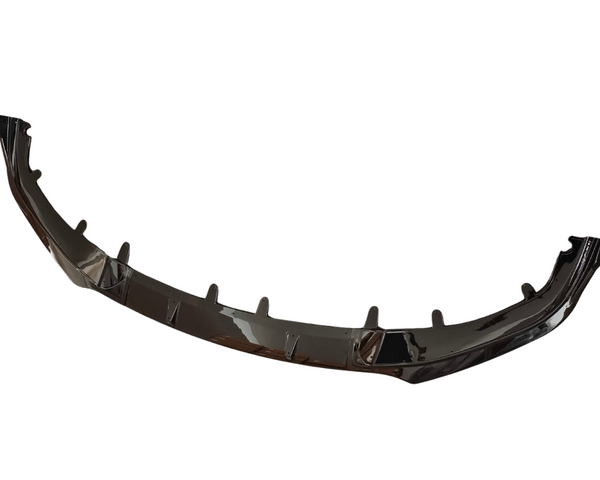 A glossy black car front splitter, featuring several vertical fins, is displayed against a plain white background, highlighting its aerodynamic design for vehicle use.