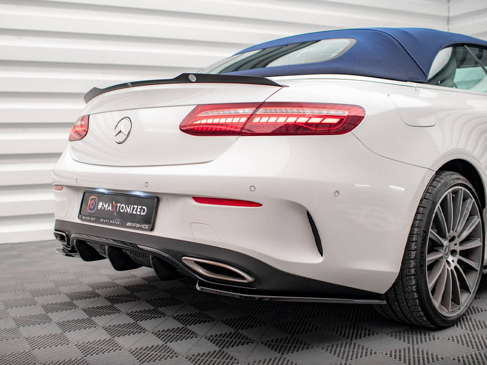 Car with white body and blue convertible top parked indoors; rear lights illuminated. The license plate reads "#MAXTONIZED" with logos for Mercedes-Benz and AMG. Ribbed white walls surround the vehicle.