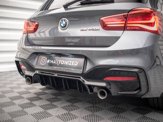 The rear of a gray BMW M440i with visible exhaust pipes is parked on a checkered floor. The license plate reads "#MAXTONIZED @URDIOMOTORS."