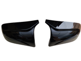 Two black car mirror covers face each other, slightly tilted inward, against a plain white background.