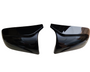 Two black car mirror covers face each other, slightly tilted inward, against a plain white background.