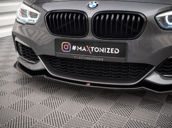 A grey car's front bumper with a prominent black grille displays a "#MAXTONIZED" plate above "CLAROMOTORS." The setting features a patterned grey floor and a modern, stylized background.