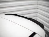 A car roof with a sleek black roof spoiler is parked inside a garage, framed by ribbed metallic walls, adding a modern touch to the minimalistic setting.