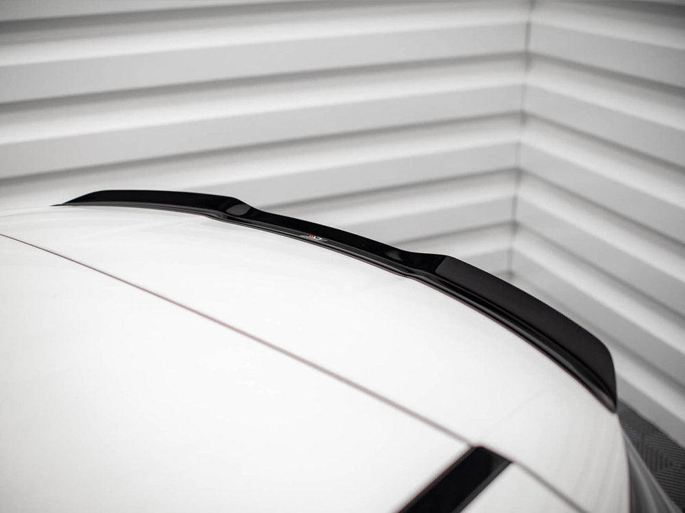 A car roof with a sleek black roof spoiler is parked inside a garage, framed by ribbed metallic walls, adding a modern touch to the minimalistic setting.