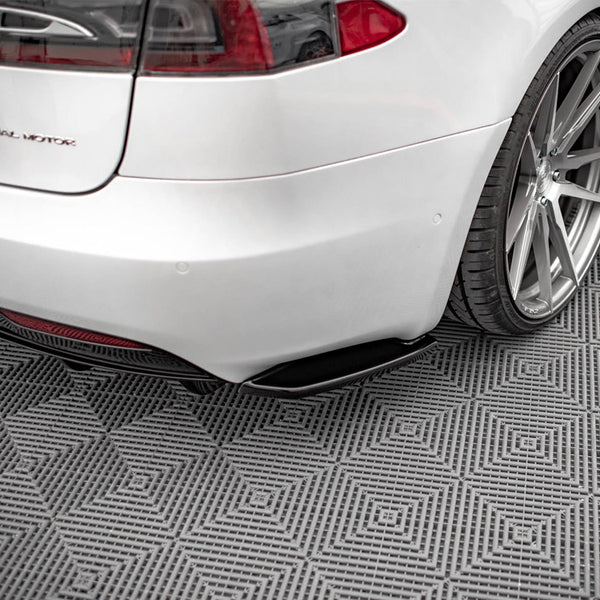 Car rear view showcases a silver vehicle with the text "D U A L M O T O R," parked on a patterned, gray floor featuring diamond designs. Subtle reflections highlight the polished surface.