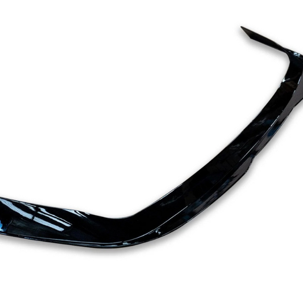 A shiny black car bumper, slightly curved, rests against a plain white background.