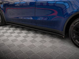 A blue car with sleek, reflective bodywork, parked on a textured geometric-patterned floor, shows partial view of a wheel and door on the right side.