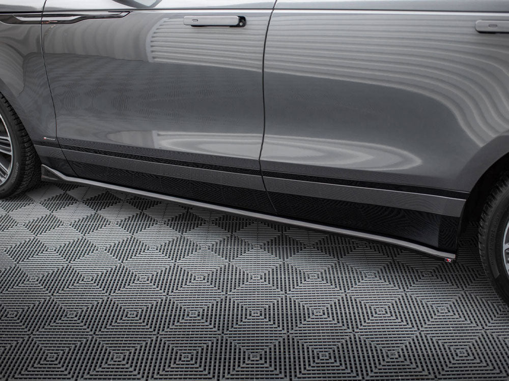 A shiny gray car door with sleek side mirror and wheel, parked on a geometric-patterned black and gray floor in a well-lit garage.