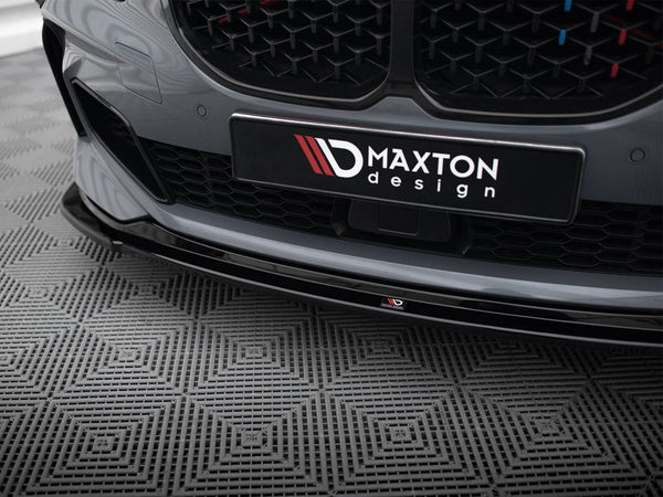 Car bumper features a "Maxton Design" logo, displayed on a patterned floor. The sleek, gray surface highlights an aesthetic grille, capturing a modern automotive design in a showroom setting.