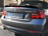 A gray BMW 220i is parked outdoors under a fabric canopy, with the text 