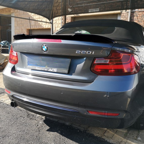 A gray BMW 220i is parked outdoors under a fabric canopy, with the text "Powered by ACS" displayed on the rear license plate area.