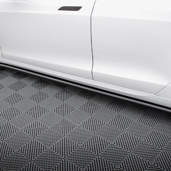 White car side, featuring sleek side skirts, parked on a patterned floor with geometric diamond shapes, creating a modern, polished appearance.