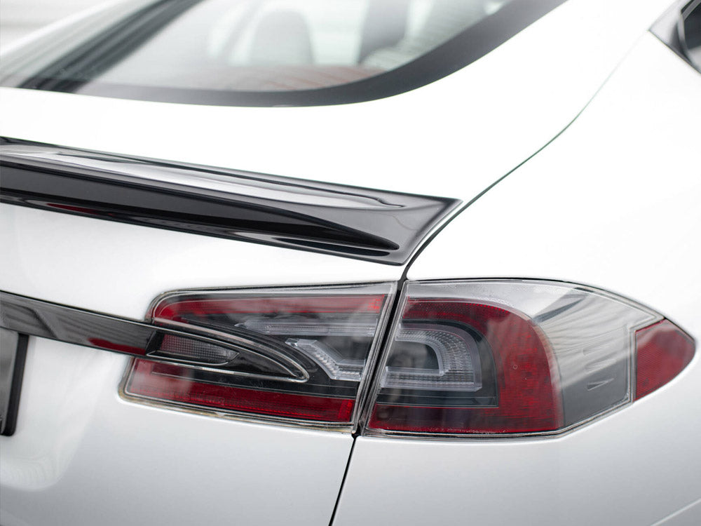A white car with a sleek black spoiler is parked, highlighting its angular, modern taillight design. The context suggests a clean, bright environment.