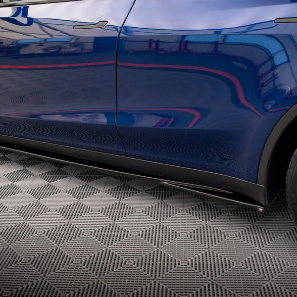 Car side profile reflecting surroundings, parked in a patterned garage. The vehicle is blue with black wheels, and the tire displays "MICHELIN" on it.
