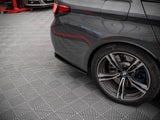 A dark gray car's rear wheel is stationary on a patterned garage floor, with a red vehicle lift partially visible in the background.