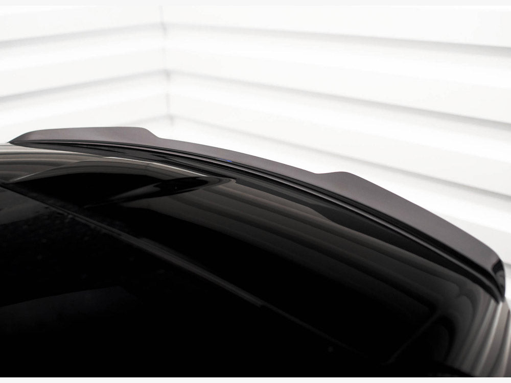 A sleek, shiny black car roof with a subtle aerodynamic spoiler is shown. The background consists of white horizontal paneling, creating a minimalistic and modern setting.
